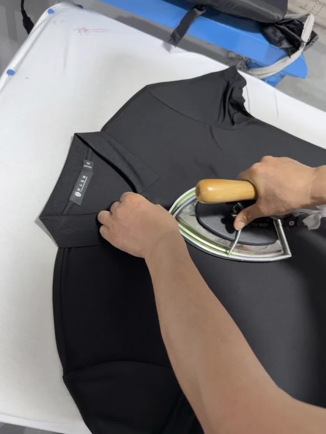 A polo shirt being pressed at a finishing station