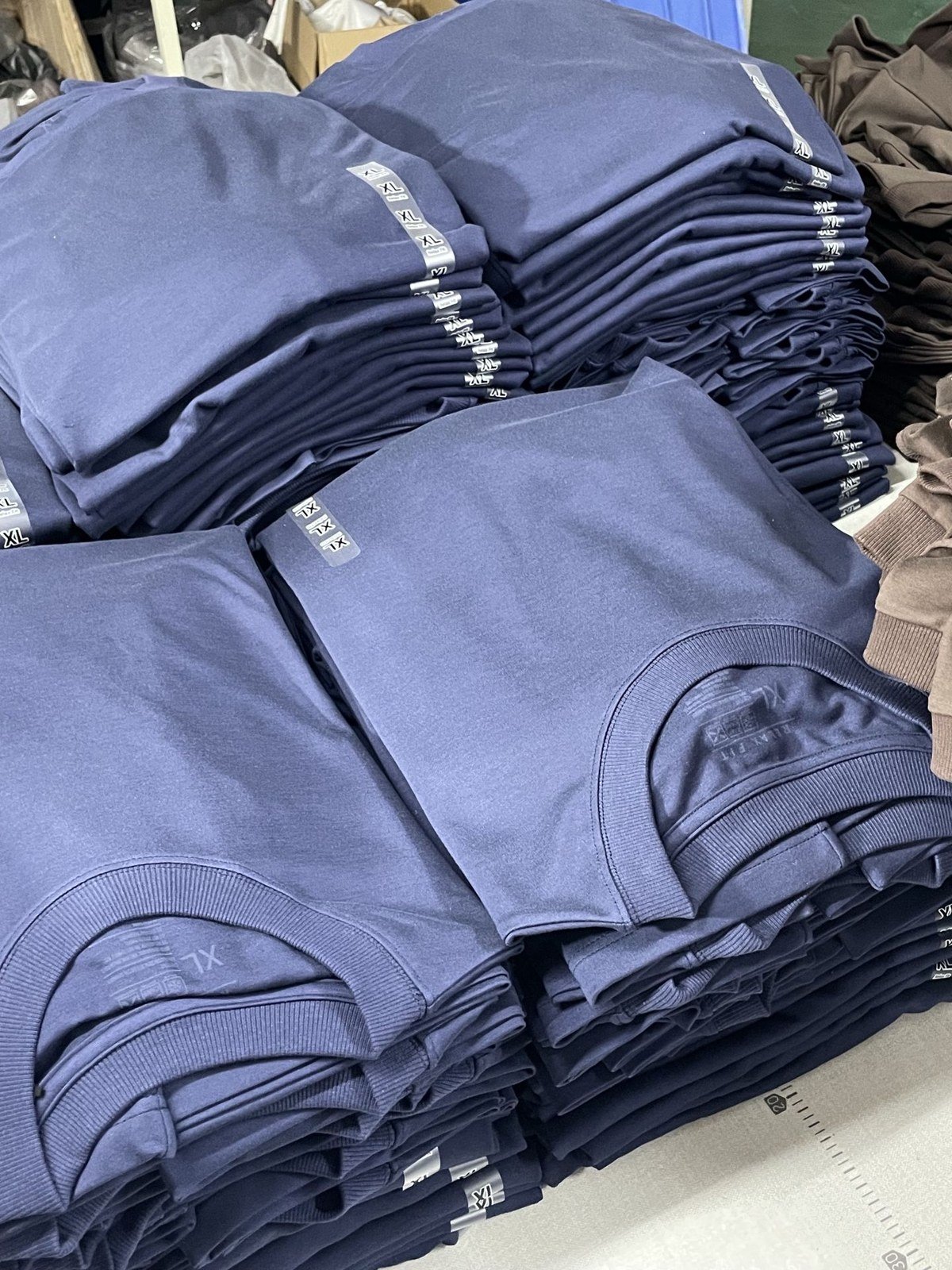 Folded T-shirts showing fabric drape and finish; confirm GSM from the specification.